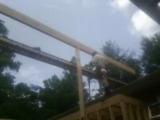 Carpenter setting a ridge beam over a new addition frame — Ice Dam Removal by Roofing Brothers in Quebeck