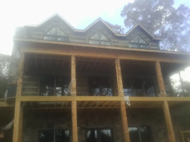 Dormers and porch framing on a large log home under construction — Roof Coating work by our crew in Quebeck