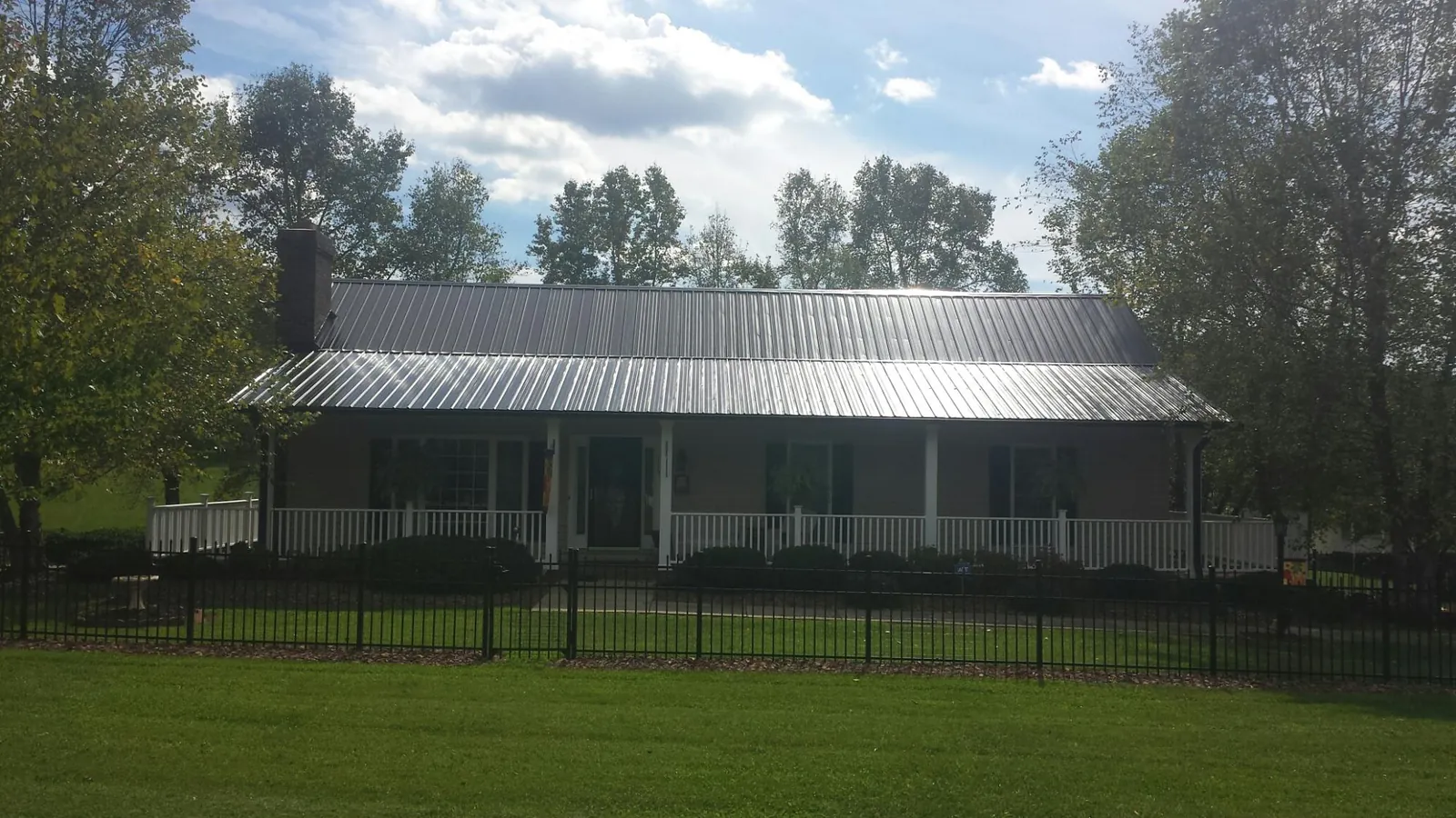 Gray metal roof on a brick ranch with a full width front porch — Gutter Guard Installation work by our crew in Quebeck