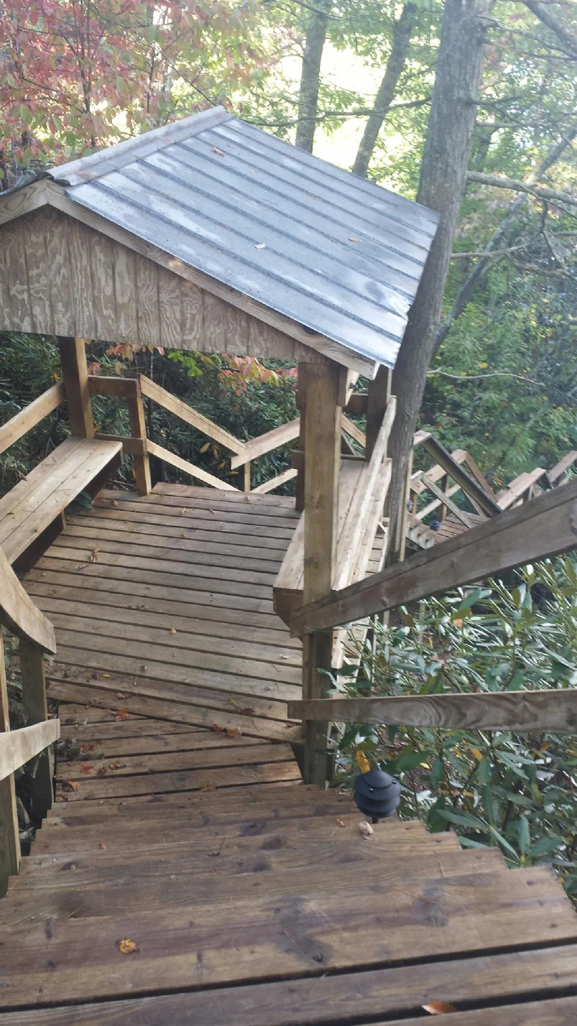 Metal roofed shelter over wooden steps on a wooded walkway — Skylight Repair & Installation work by our crew in Quebeck